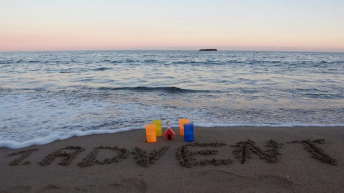 Im Hintergrund das Meer, im Vordergrund 4 Kerzen und in den Sand geschrieben "1. Advent"